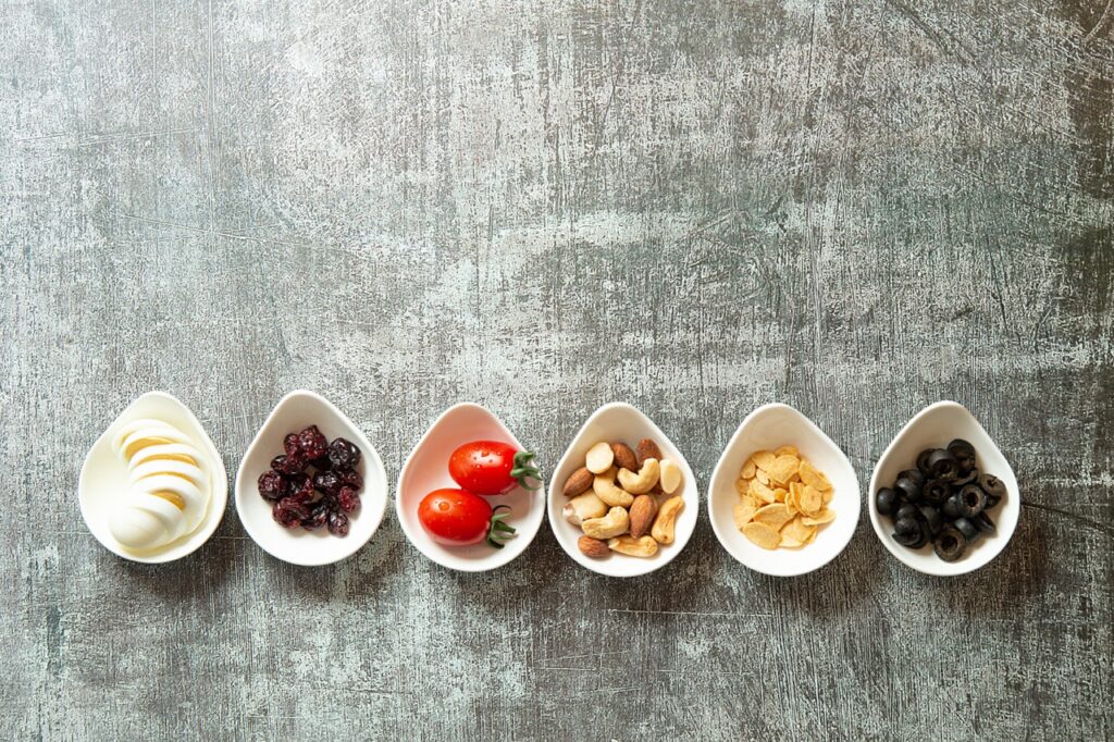 a row of small white bowls with various nuts and snacks