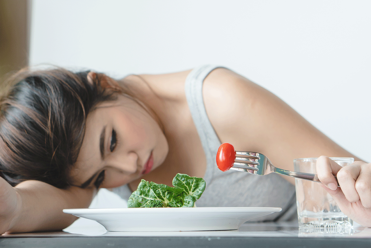 Sad woman eating salad.