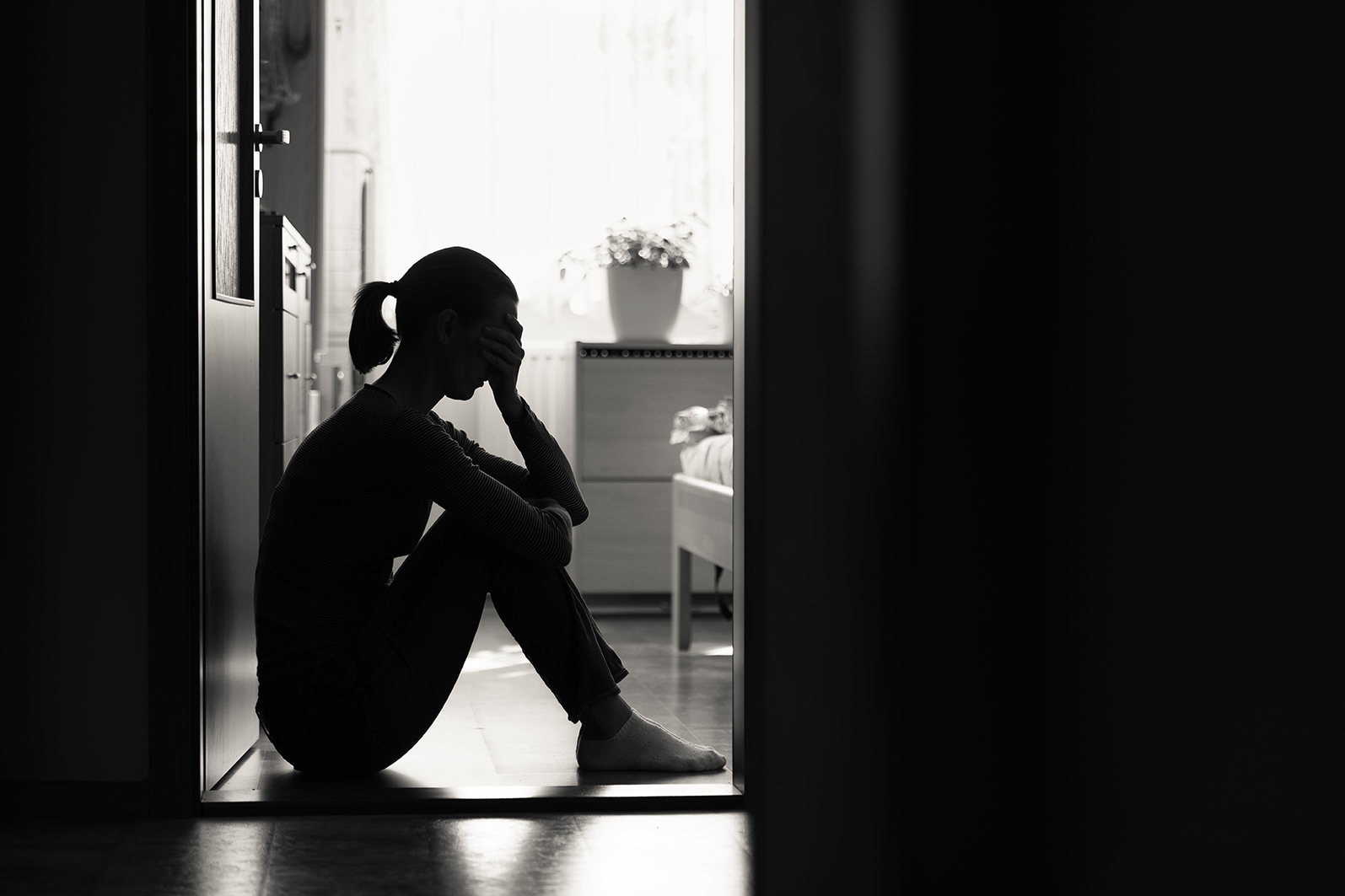 Sad woman sitting in doorframe